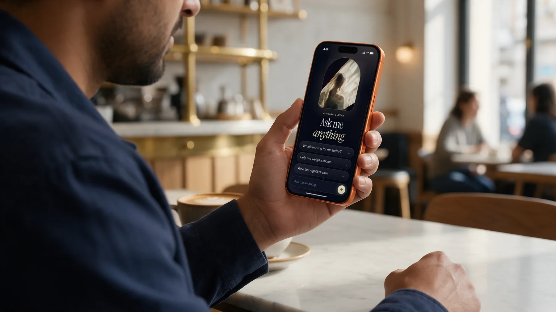 A man in a café holding his phone, open on a new conversation with Auriana